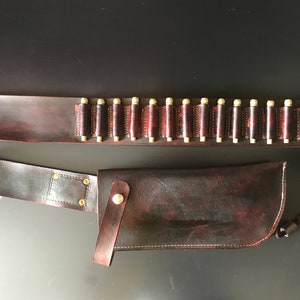 May include: A brown leather belt with a cartridge holder and a matching brown leather holster. The belt has 20 cartridge loops and the holster has a flap with a snap closure.