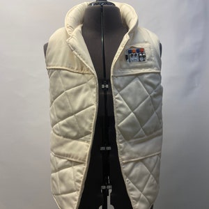 May include: A white quilted vest with a patch on the left side featuring a colorful design and the text "Rebel Alliance".