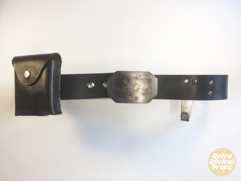 May include: A black leather belt with a silver buckle and a small black leather pouch attached. The belt has silver rivets and a silver hook.