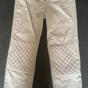 Puede incluir: Un pantalón gris claro con rodilleras acolchadas.