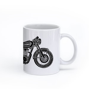 Op de afbeelding: Een witte keramische mok met een zwart silhouet van een motorfiets aan de ene kant. De motorfiets heeft een ronde koplamp en een enkel voorwiel.