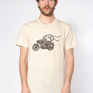 May include: A beige t-shirt with a black and white graphic of an octopus riding a motorcycle.