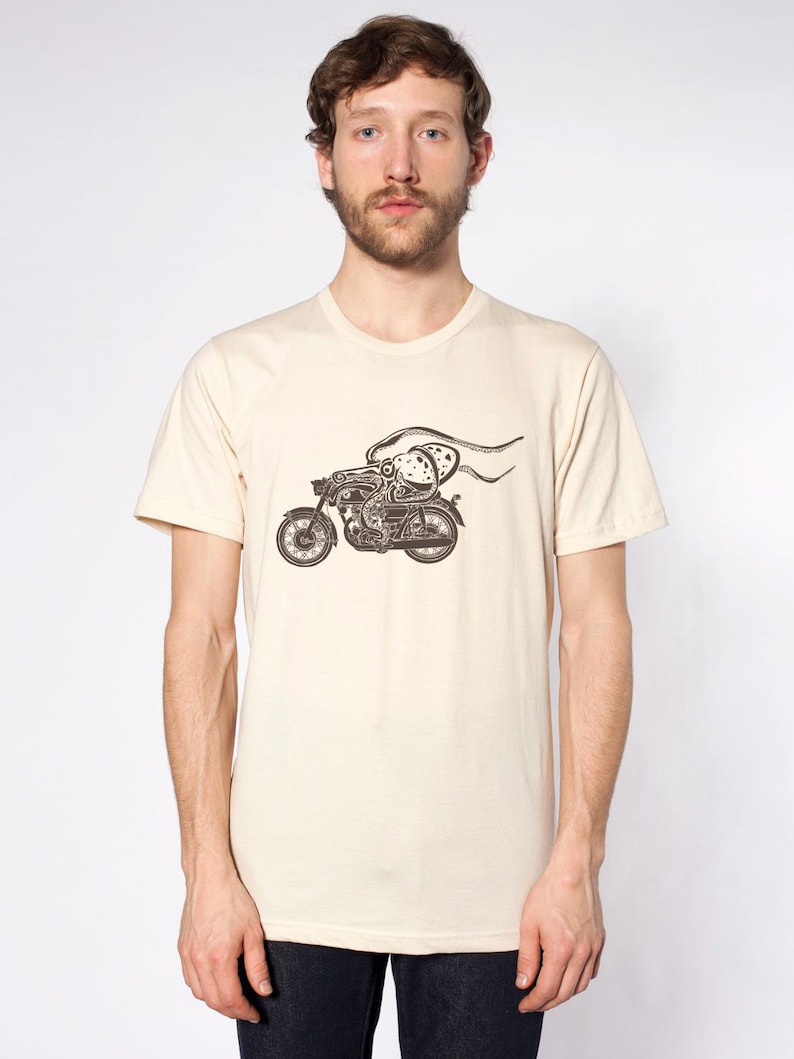 May include: A beige t-shirt with a black and white graphic of an octopus riding a motorcycle.
