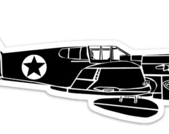 May include: Black and white sticker of a vintage fighter plane. The aircraft features a star emblem on the side and a shark mouth design on the nose. The propeller is visible at the front.