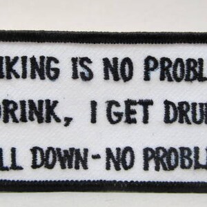 Könnte beinhalten: Weißer Patch mit schwarzem gesticktem Text, der lautet: "Trinken ist kein Problem, ich trinke, ich werde betrunken, ich falle hin - kein Problem."