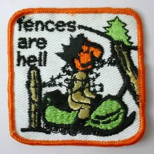 May include: A white embroidered patch with an orange border. The patch features a cartoon character with a pumpkin head, wearing a green and black outfit, and the text "Fences are hell".