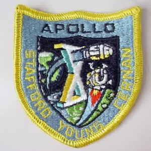 May include: A blue and yellow embroidered patch with the text "APOLLO" at the top, "STAFFORD YOUNG CERNAN" around the edges, and a stylized rocket ship in the center.