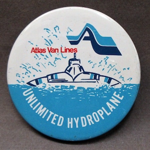 May include: A white and blue round pin with the text "Atlas Van Lines" and "Unlimited Hydroplane". A blue and white stylized hydrofoil boat is in the center of the pin.