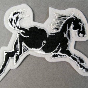 Può includere: Toppa ricamata di colore nero con la silhouette di un cavallo su uno sfondo bianco. Il cavallo corre con la criniera al vento.