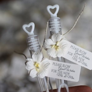 May include: Two white plastic bubble wands with white paper flowers and tags that read "Please Blow Good Wishes for the New Mr. & Mrs."