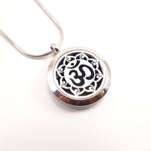 May include: Silver pendant necklace with an Om symbol inside a circular design. The pendant is a diffuser and can be used with essential oils.