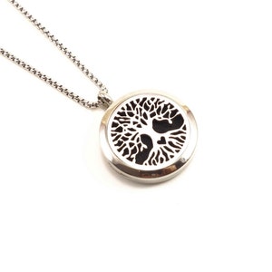 May include: A silver necklace with a round pendant featuring a tree of life design. The pendant is black and white and has a detailed design.