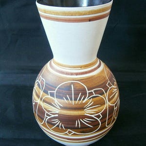 以下が含まれることがあります： 茶色と白の花柄の白い陶器の花瓶。花瓶は口が広く、首が細い。