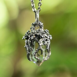 May include: A silver necklace with a clear crystal pendant encased in a delicate silver tree branch design.