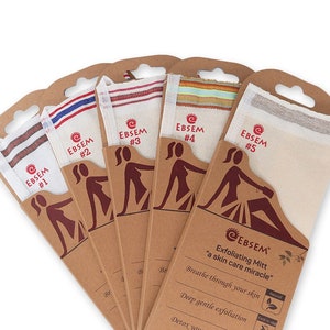 Puede incluir: Conjunto de cinco guantes exfoliantes empaquetados en cajas de cartón marrón con fondo blanco. Cada guante está etiquetado con un número del 1 al 5. Las cajas muestran a una mujer usando el guante y el texto "EBSEM Guante exfoliante - un milagro para el cuidado de la piel".
