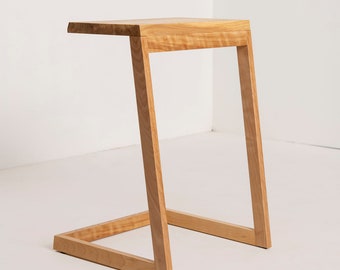 May include: A wooden side table with a simple, modern design. The table has a rectangular top and a unique angled base.
