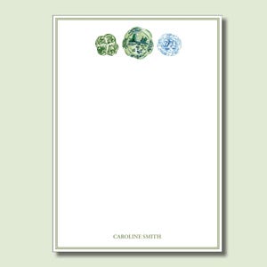 May include: White stationery with a green and blue floral design. The stationery has a thin green border and the name "CAROLINE SMITH" printed at the bottom. Three floral designs are at the top of the stationery.