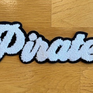 May include: White fluffy patch with the word "Pirates" in black outlined letters.