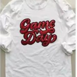 May include: White long-sleeve shirt with the words "Game Day" in red, cursive lettering across the front. The shirt has a crew neck and the sleeves are three-quarter length.