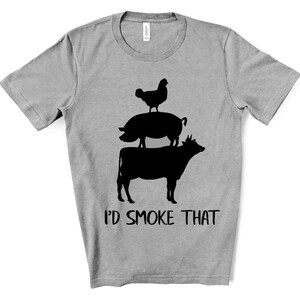 May include: A gray t-shirt with a black silhouette of a cow, pig, and chicken stacked on top of each other. The text "I'd smoke that" is printed below the animals.