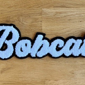 May include: White fluffy "Bobcats" lettering in a cursive font with a black outline.
