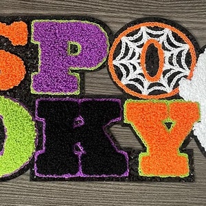 May include: A sparkly, colorful felt banner that reads "SPOOKY" with a spiderweb and a ghost.