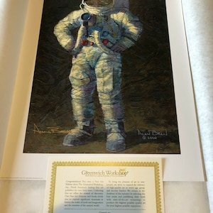 May include: Fine art print depicting an astronaut in a spacesuit, hands on hips, holding a camera. Signed by Alan Bean, dated 2000. Includes a certificate from Greenwich Workshop.