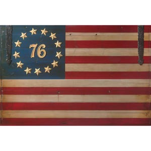 May include: Wooden American flag with red and white stripes and a blue field with gold stars and the number 76. The flag has a rustic, vintage appearance, with visible wood grain and metal hinges.