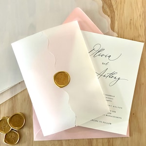 Peut inclure: Suite de faire-part de mariage avec une carte blanche et une écriture élégante, scellée d'un cachet de cire doré. L'invitation est superposée à une enveloppe rose, avec de la papeterie supplémentaire visible. Le texte se lit "Olivia et Anthony".