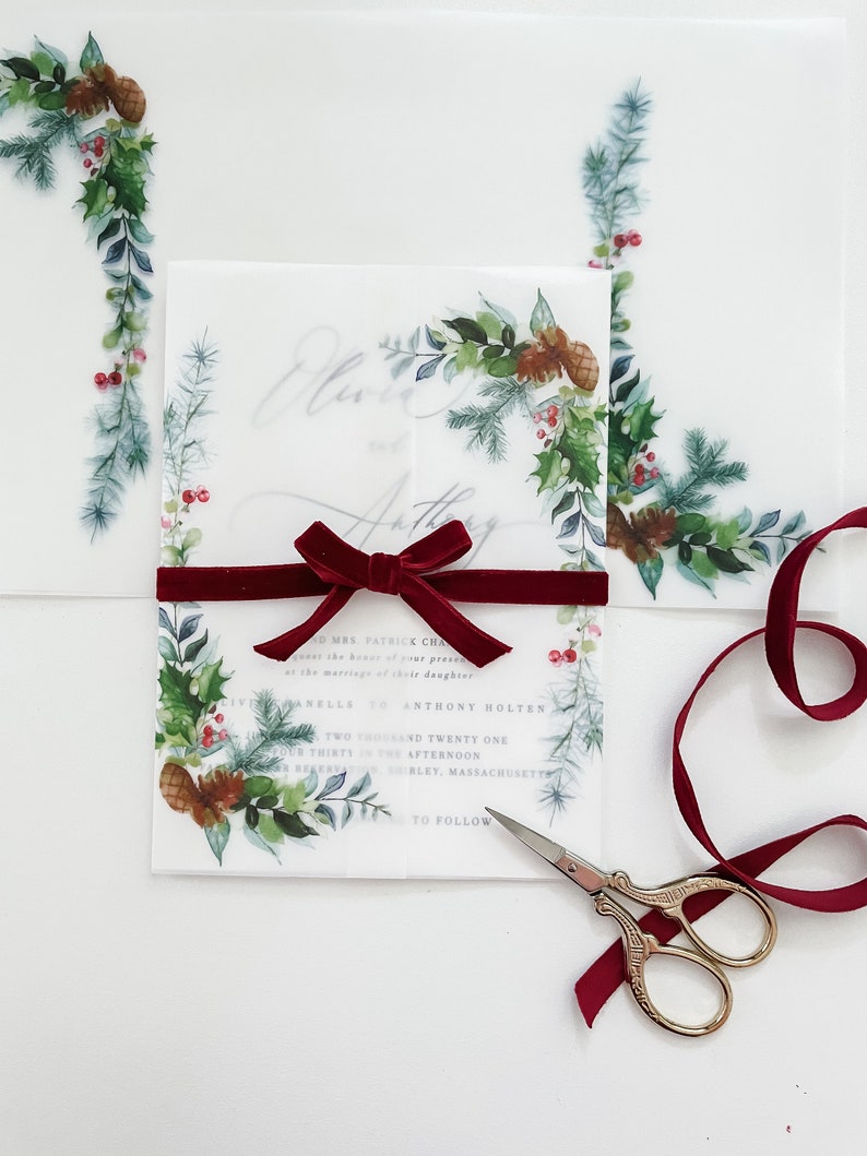 Christmas evergreen 5x7 vellum invite jacket with greenery and pine cone designs on the corner. Clear vellum wrap is wrapped around a 5x7 wedding invitation and meets in the middle.