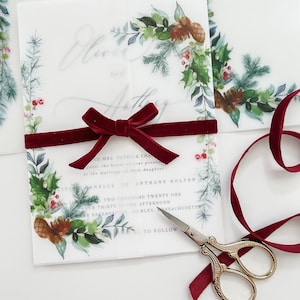 Greenery Holiday 5x7 vellum wrap jacket with evergreen wreath designs on the corner. The vellum jacket is wrapped around a 5x7 wedding invitation and meets in the middle.