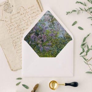 May include: A white envelope with a pointed flap featuring an interior liner printed with an impressionistic painting of purple lilac flowers and green foliage. The envelope is displayed open to reveal the floral pattern inside the paper structure.