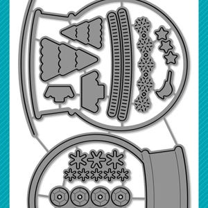 Può includere: Un set di fustelle in metallo grigio per il crafting, con varie forme per costruire una palla di neve. Include fiocchi di neve, stelle, alberi e componenti del globo. Il testo "lawn cuts" e "Build-A-Snow Globe" sono visibili.