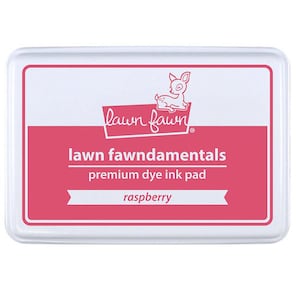 May include: A white ink pad with a pink border and the text "lawn fawn" and "lawn fawnamentals premium dye ink pad" in black. The ink pad is labeled "raspberry".