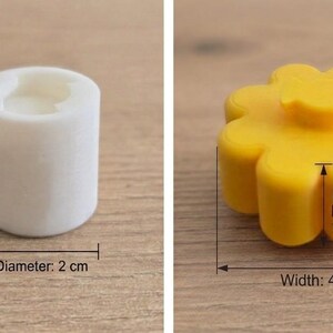 K&ouml;nnte beinhalten: Eine wei&szlig;e zylindrische Form mit einer H&ouml;he von 2 cm und einem Durchmesser von 2 cm sowie eine gelbe blumenf&ouml;rmige Form mit einer Blumenh&ouml;he von 2,5 cm und einer Breite von 4 cm. Beide Artikel sind mit klaren Beschriftungen ihrer Ma&szlig;e versehen.