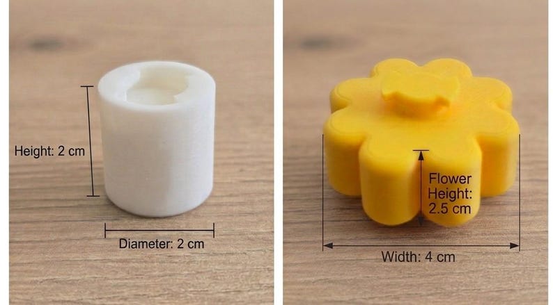 K&ouml;nnte beinhalten: Eine wei&szlig;e zylindrische Form mit einer H&ouml;he von 2 cm und einem Durchmesser von 2 cm sowie eine gelbe blumenf&ouml;rmige Form mit einer Blumenh&ouml;he von 2,5 cm und einer Breite von 4 cm. Beide Artikel sind mit klaren Beschriftungen ihrer Ma&szlig;e versehen.