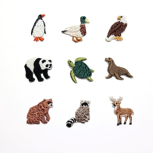 Könnte beinhalten: Neun aufgestickte Tieraufnäher: Pinguin, Ente, Adler, Panda, Schildkröte, Seehund, Bär, Waschbär und Hirsch. Die Aufnäher sind detailliert gestickt und in verschiedenen Farben gehalten, ideal zum Aufnähen auf Kleidung.