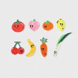 Pode incluir: Patches bordados com várias frutas e vegetais sorridentes. Inclui um tomate vermelho, um pêssego rosa, uma tangerina laranja, um limão amarelo, cerejas vermelhas, uma banana amarela, uma cenoura laranja e cebolinha verde.
