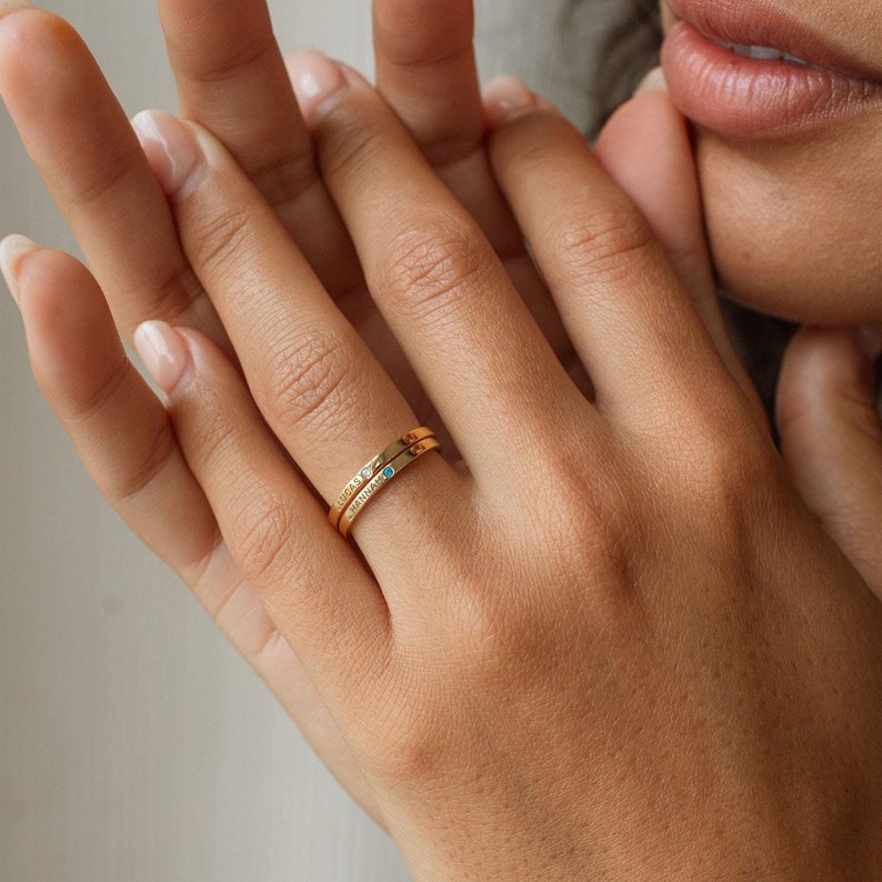 Woman wearing a dainty gold thin band ring on finger