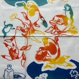 May include: A white fabric with a colorful design of fish, frogs, and flowers. The fish are orange, yellow, and red. The frogs are green and blue. The flowers are yellow and white.
