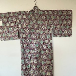 May include: A traditional Japanese kimono with a floral pattern in shades of purple, green, and white.