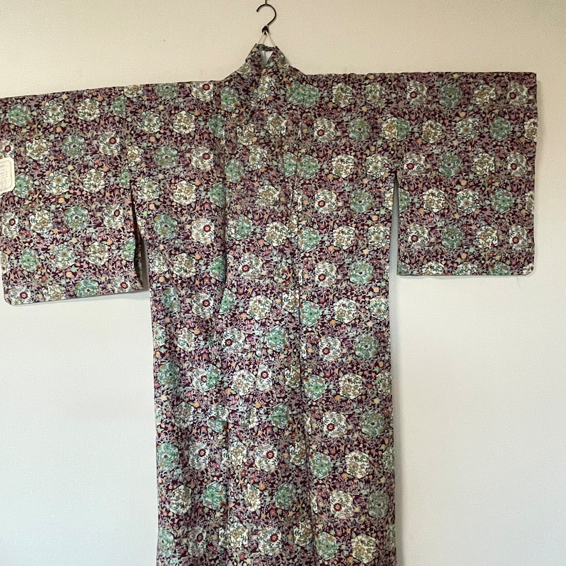 May include: A traditional Japanese kimono with a floral pattern in shades of purple, green, and white.
