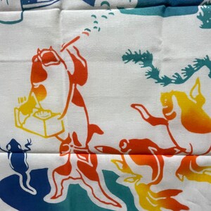 May include: A white fabric with a colorful design featuring a fish, a frog, and a seahorse. The fish is orange and red, the frog is blue, and the seahorse is yellow and orange.