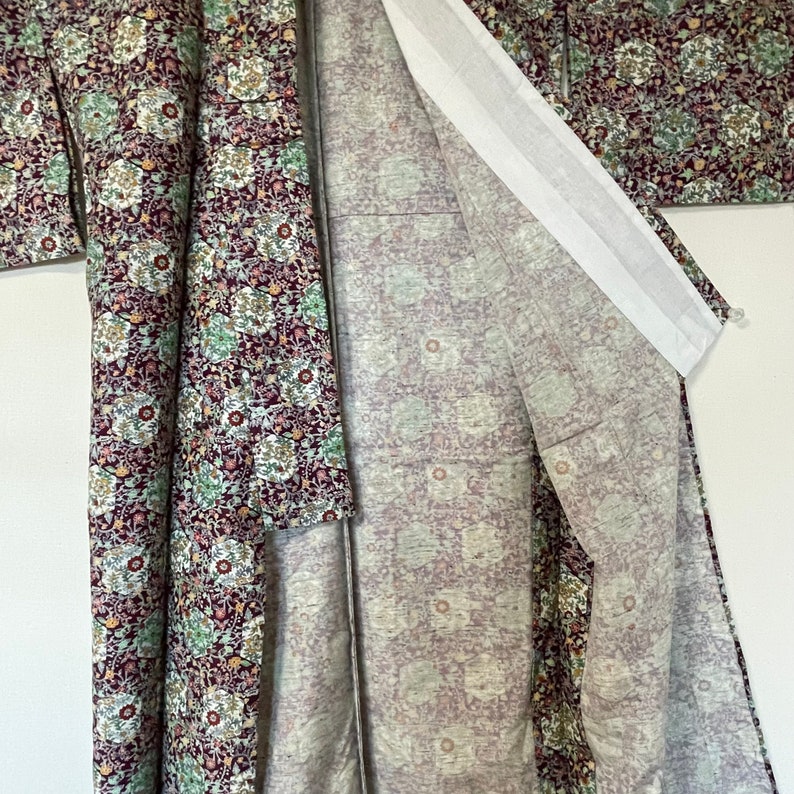 May include: A traditional Japanese kimono with a floral pattern in shades of purple, green, and white. The kimono is made of a soft, lightweight fabric and has a long, flowing silhouette.