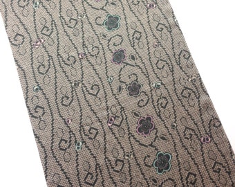 May include: A brown fabric with a repeating pattern of black squares and wavy lines. The fabric is decorated with small pink, blue, and green flowers.