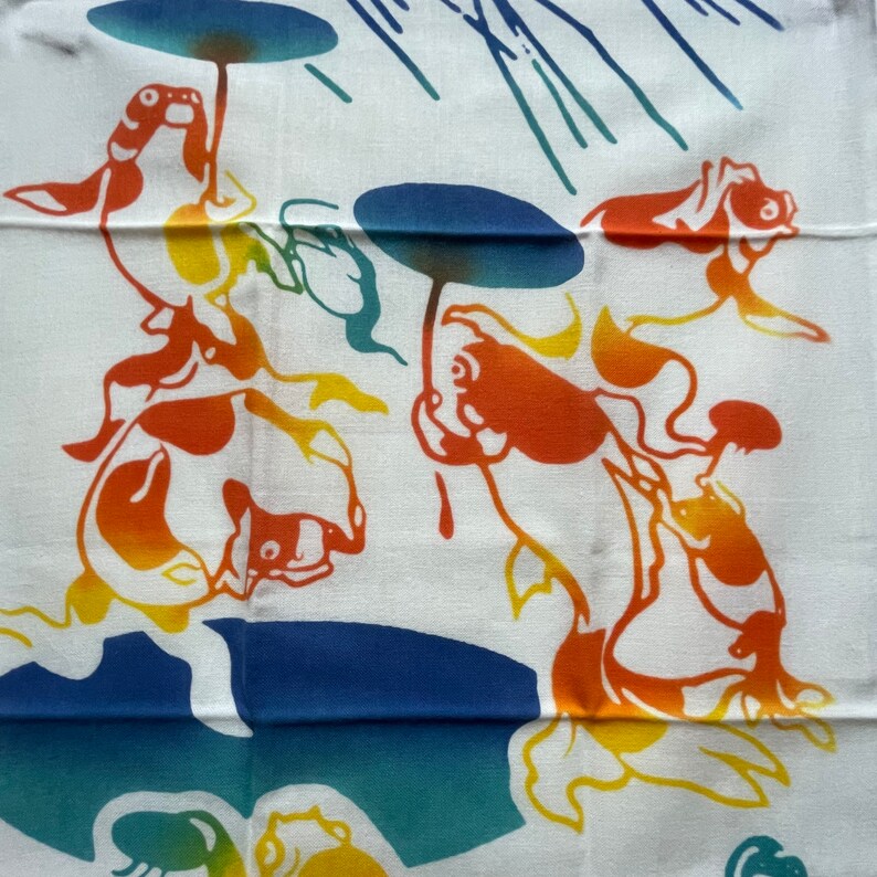 May include: A white fabric panel with a colorful design of stylized fish holding umbrellas. The fish are orange, yellow, and blue. The umbrellas are blue and green. The background is white with blue and green lines.