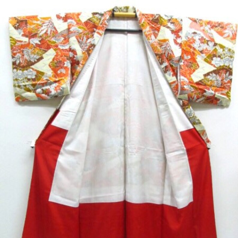 Puede incluir: Un kimono japon&eacute;s tradicional con fondo blanco y un estampado floral colorido. El kimono est&aacute; abierto para revelar un forro rojo.