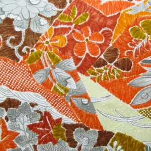 Puede incluir: Una tela blanca con un estampado floral colorido. El estampado presenta flores y hojas de color naranja, marr&oacute;n y verde. La tela tiene una superficie texturizada.
