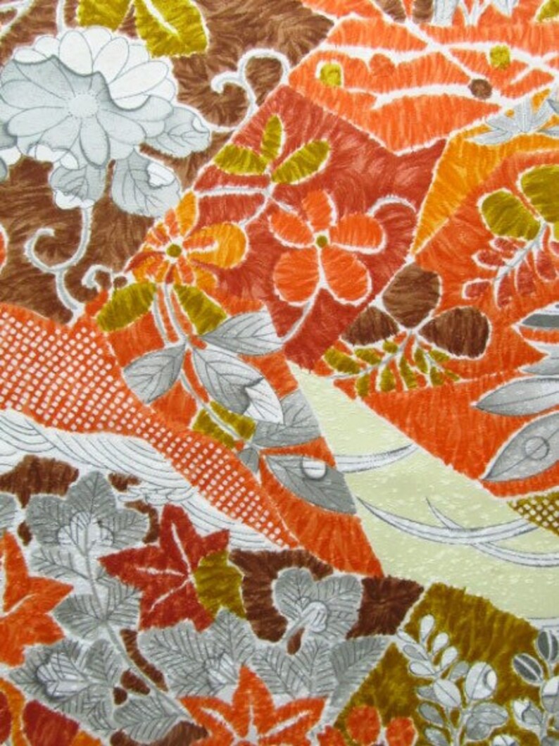 Puede incluir: Una tela blanca con un estampado floral colorido. El estampado presenta flores y hojas de color naranja, marr&oacute;n y verde. La tela tiene una superficie texturizada.