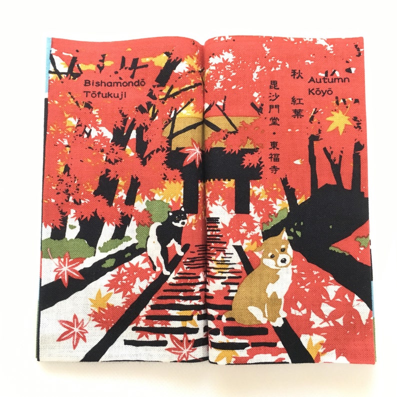 Op de afbeelding: Een open boek met een rode en zwarte illustratie van een pad door een bos met rode en gele bladeren. De tekst op het boek luidt "Autumn Koyo" en "Bishamondo Tofukuji".